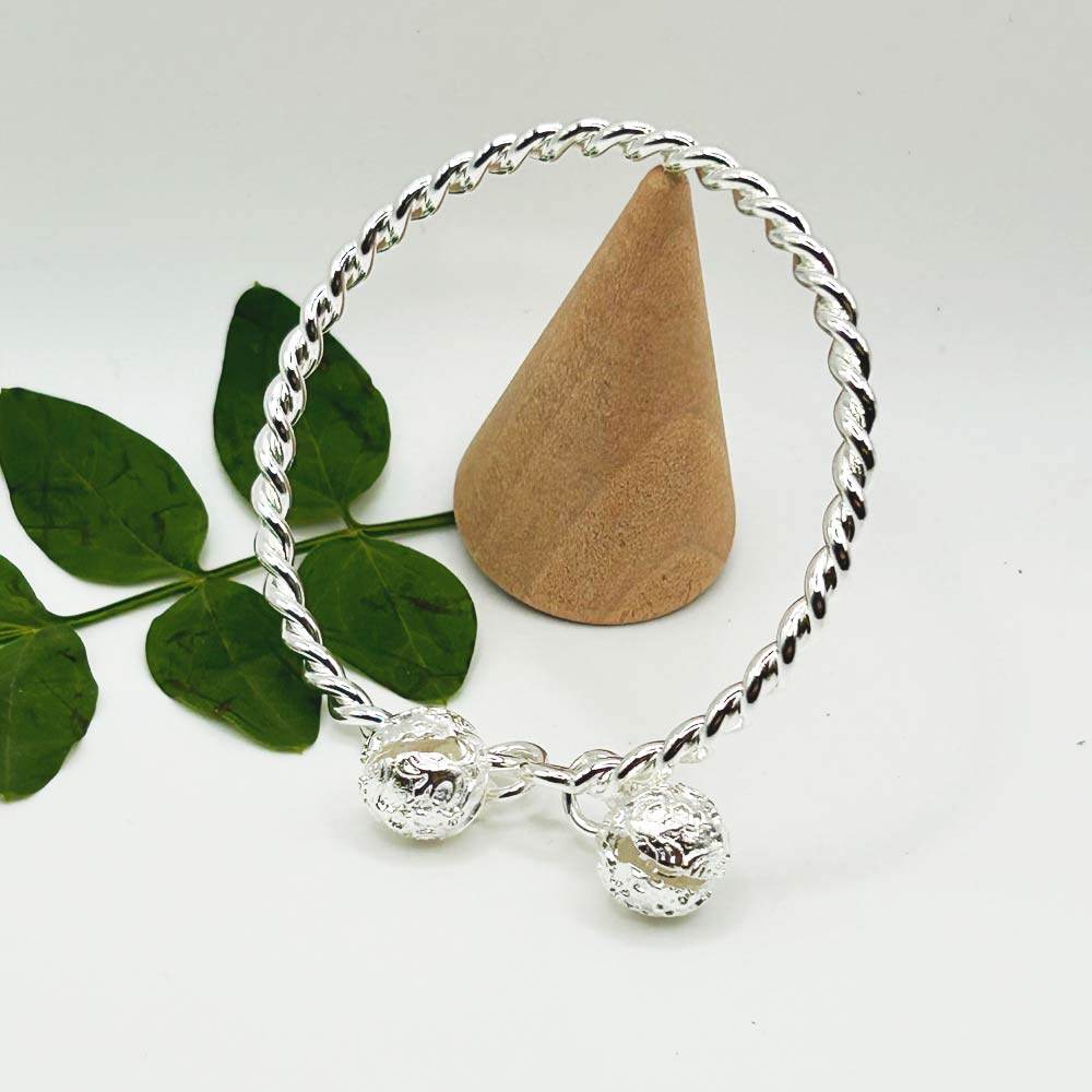 Pulsera Ema de plata con diseño trenzado y dijes en los extremos